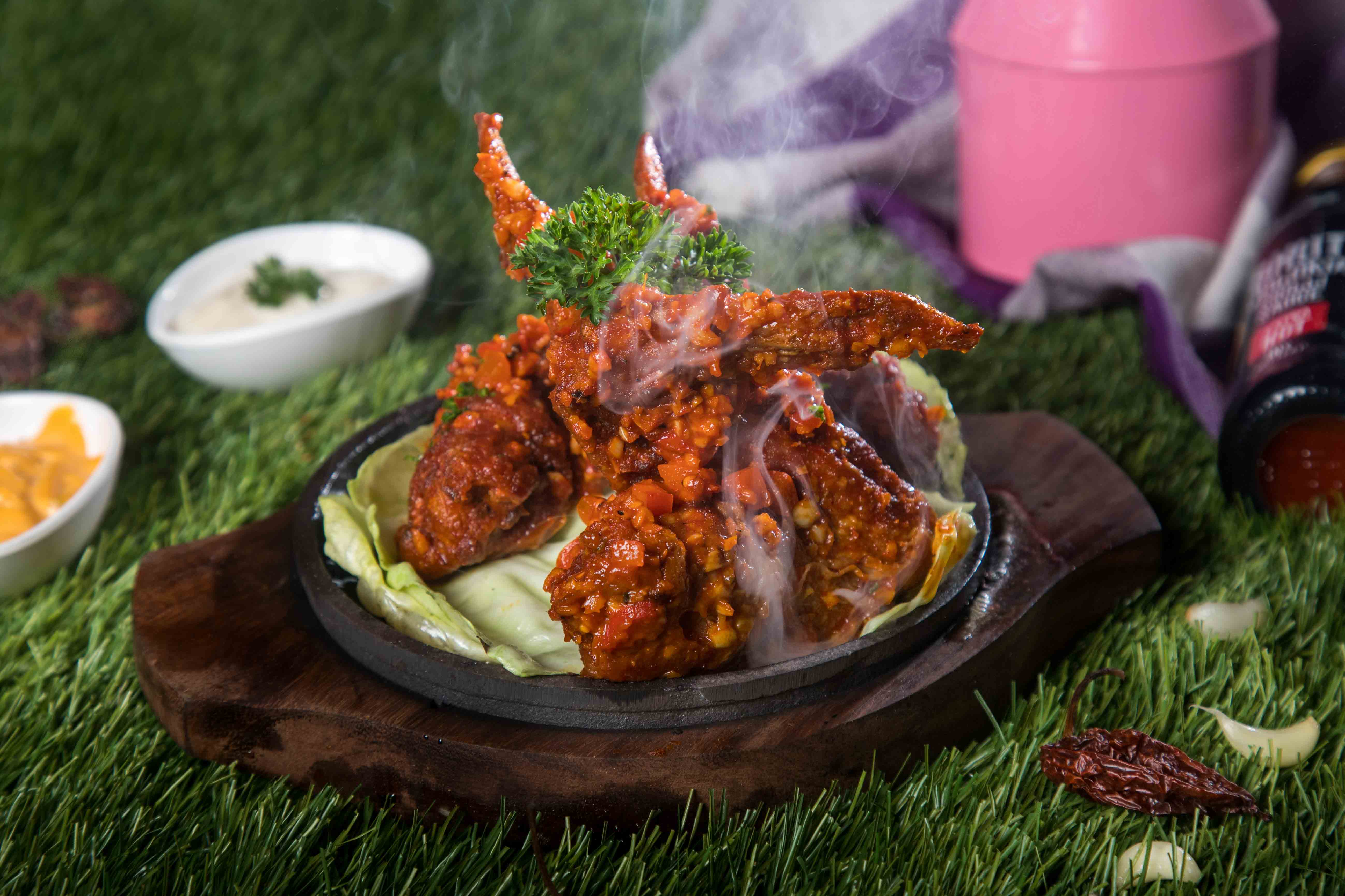 fusion chicken sizzler image decorated with ingredients and side dishes like dips drinks and spices
