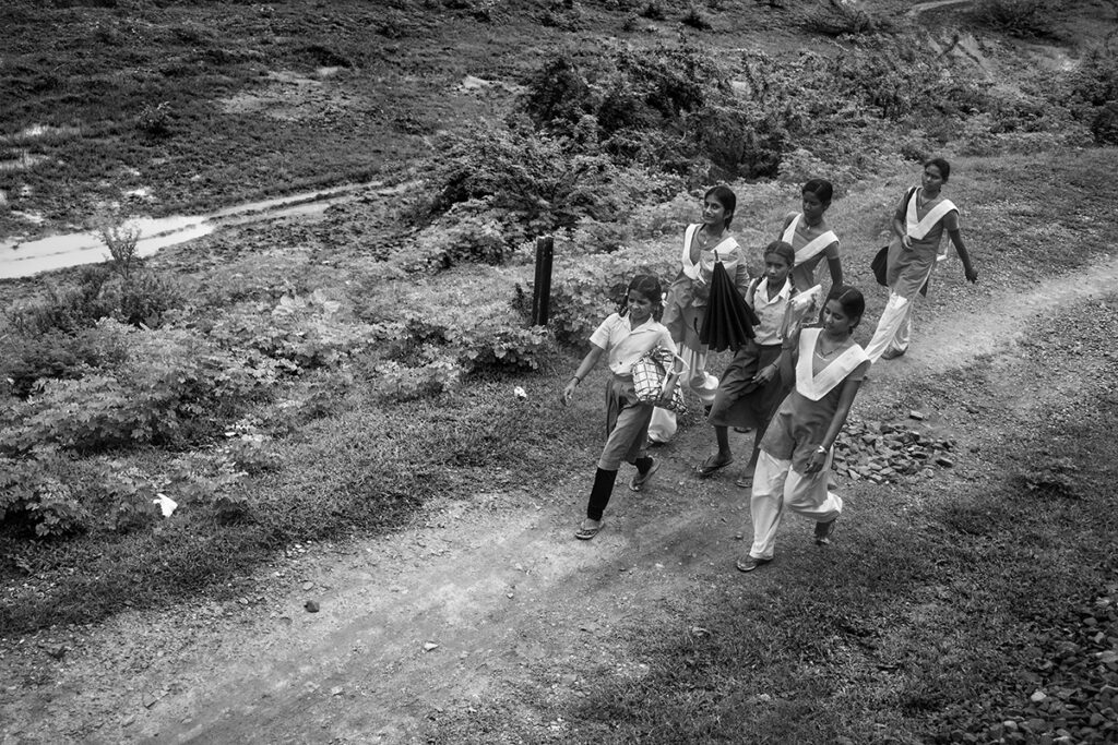 a group of young girls going to school as seen from a passing train in rural India