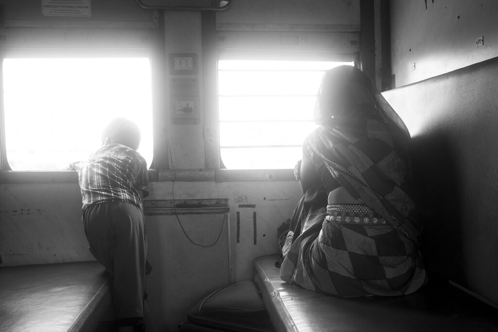 a mother and child looking out of a window on a train in India