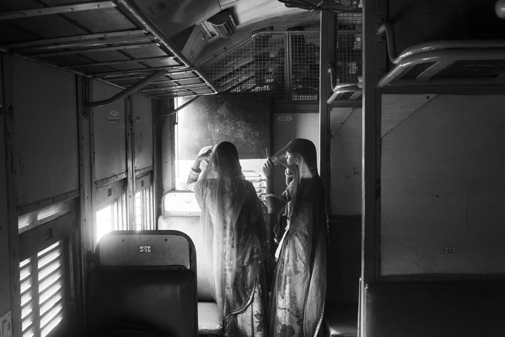 a couple of women in traditional Rajasthani clothes on a train in India