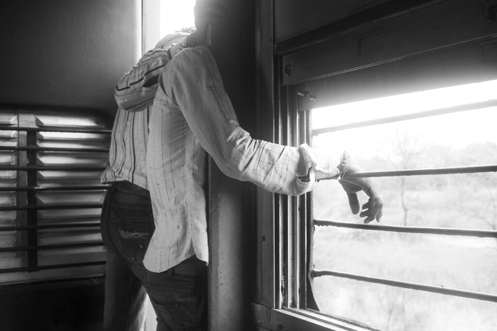 a couple of friends standing a the door of the train enjoying a cool morning breeze in India