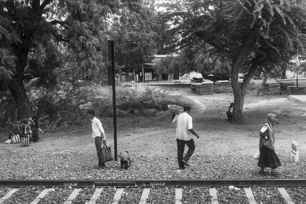 a varied group of people waiting for a train in a remote forest railway station in central India